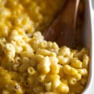 Mac and cheese in a white baking dish with a spoon ready to serve.