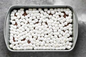 A pan of baked brownies with marshmallows on top.