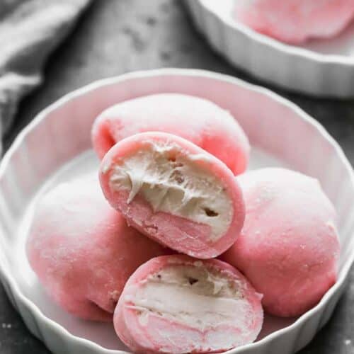 Four Mochi Ice Cream balls on a plate with one cut in half to show the ice cream center.