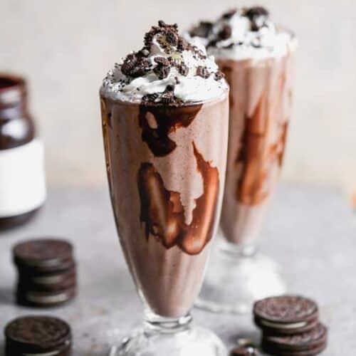 Two fountain shoppe glasses filled with Oreo milkshakes.