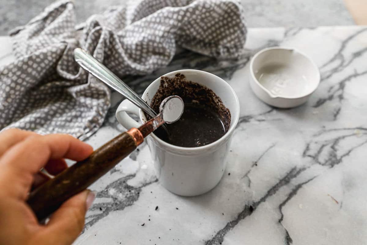 Baking powder added to a mug of crushed Oreos and milk.