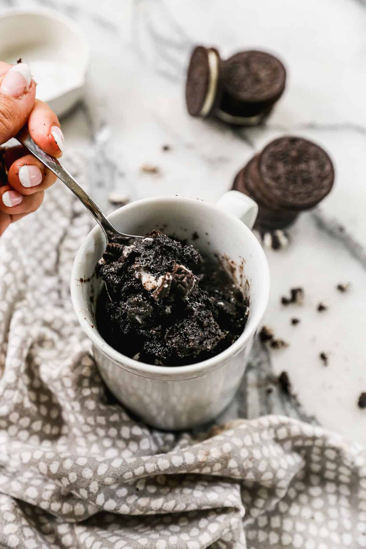 A scoop of Oreo mug cake being lifted from a mug, to show the gooey center of the cake.