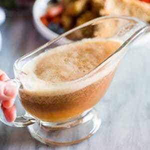 Homemade syrup in a gravy boat with french toast and fruit in the background.