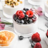 Italian Panna Cotta in a glass dish and topped with a berry sauce.