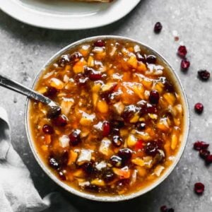 Peach chutney served in a bowl with a spoon.