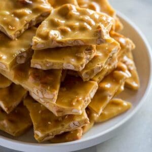 A plate with pieces of peanut brittle stacked on it.