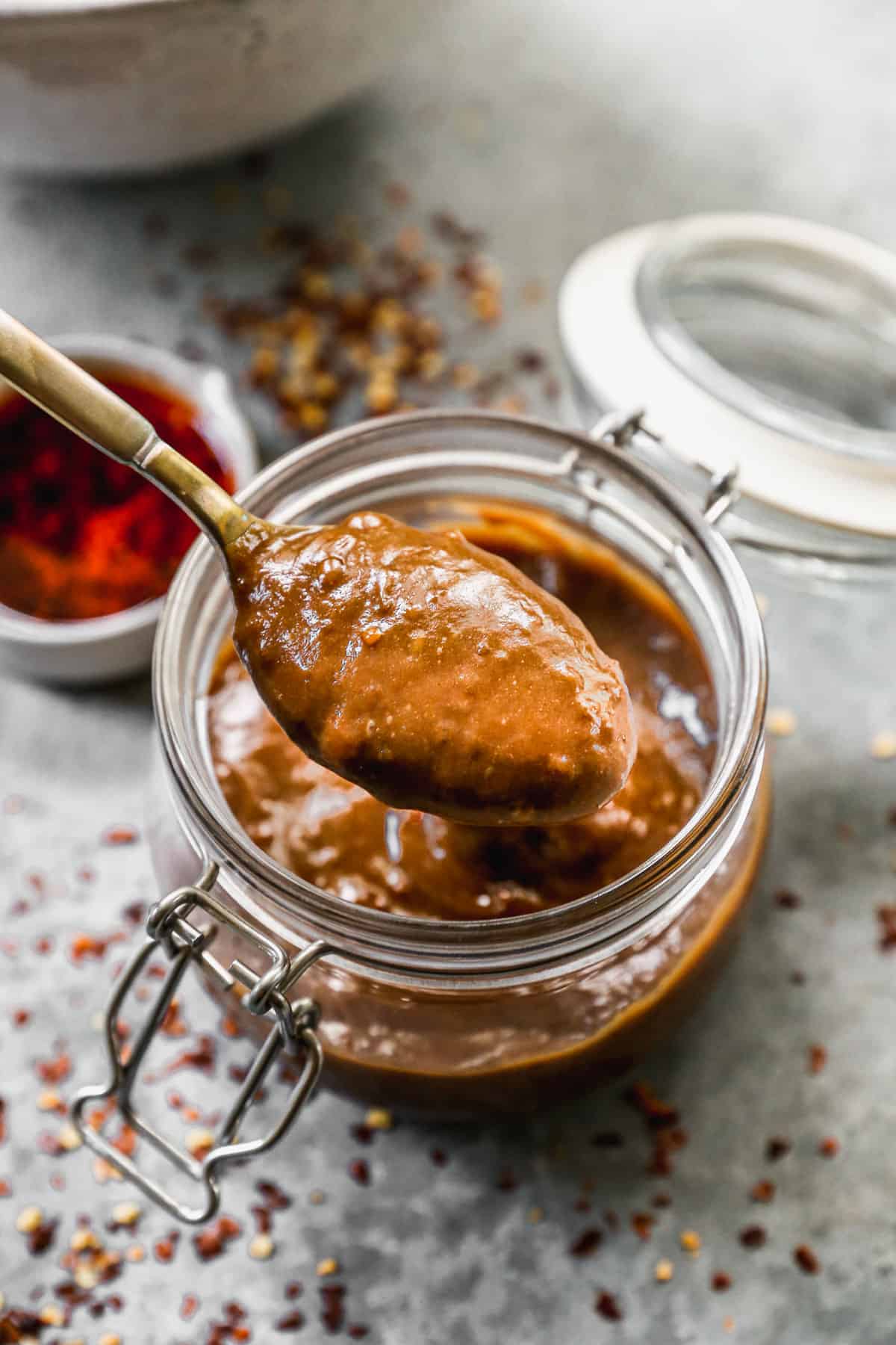 A spoonful of peanut sauce being lifted from the jar to show it's smooth texture.