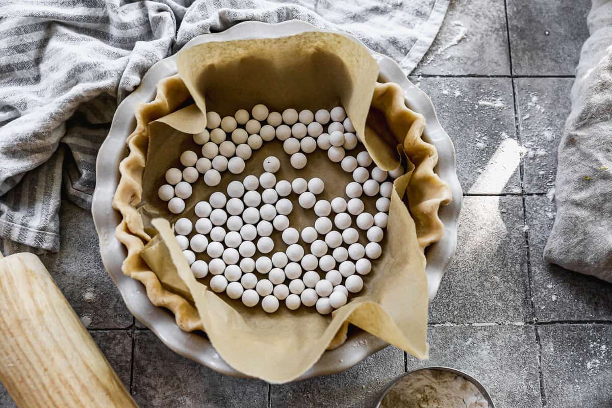 An easy pie crust, unbaked and lined with parchment paper with pie weights.