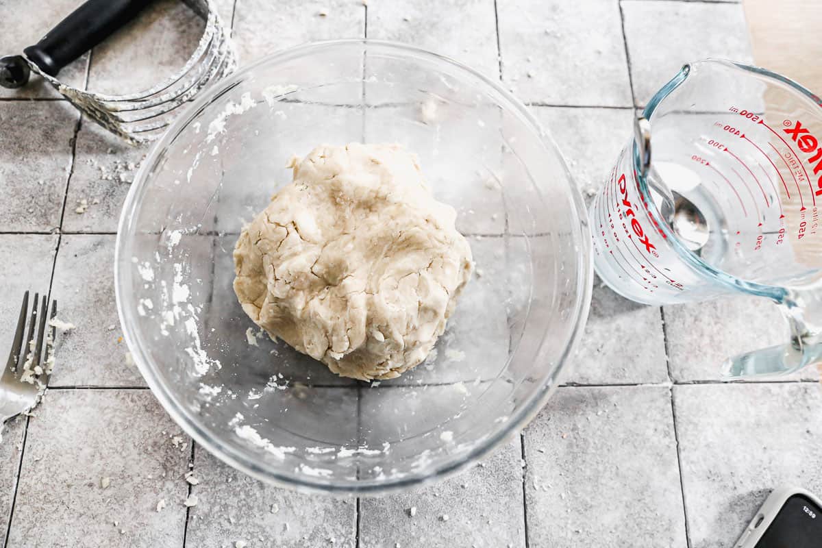 A ball of pie dough in a glass bowl.