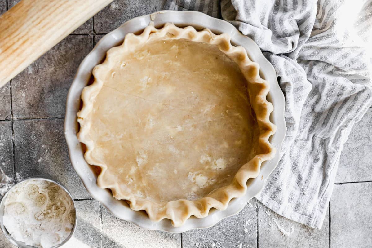 A pie crust in a pan dough with crimped edges.