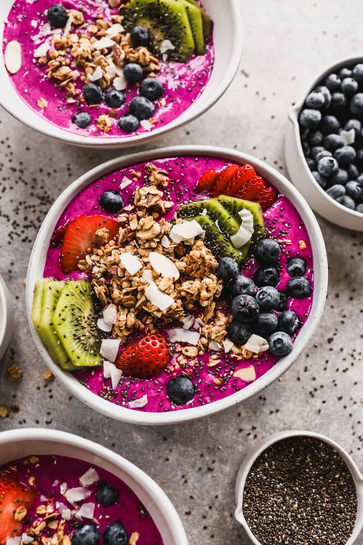 Easy Pitaya Bowls topped with homemade granola, strawberries, blueberries, kiwi, chia seeds, and shredded coconut. 