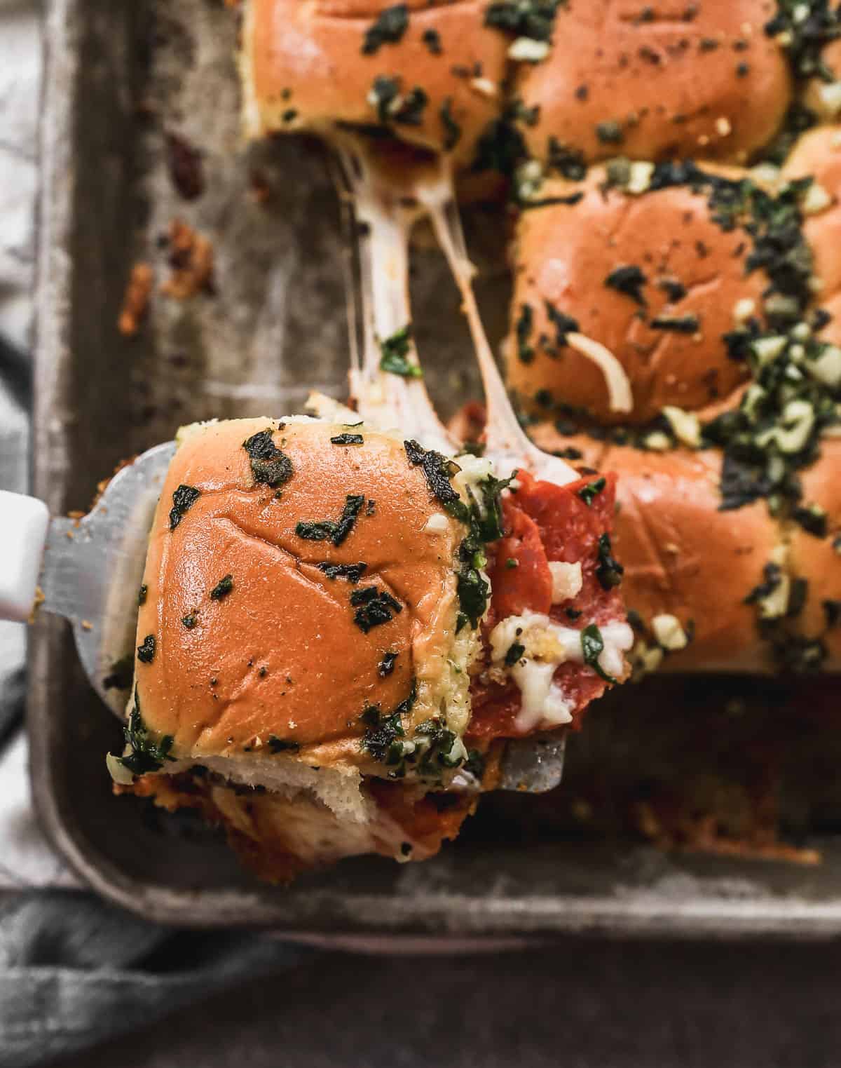 The best Pizza Slider being pulled away by a spatula, showing the melted cheese being pulled apart.