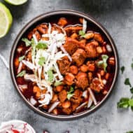 Mexican Pazole in a bowl topped with shredded cabbage, sliced radishes, and cilantro.