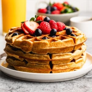 Three protein waffles stacked on top of each other and topped with fresh berries.