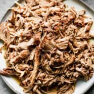 A pile of pulled pork on a white plate.