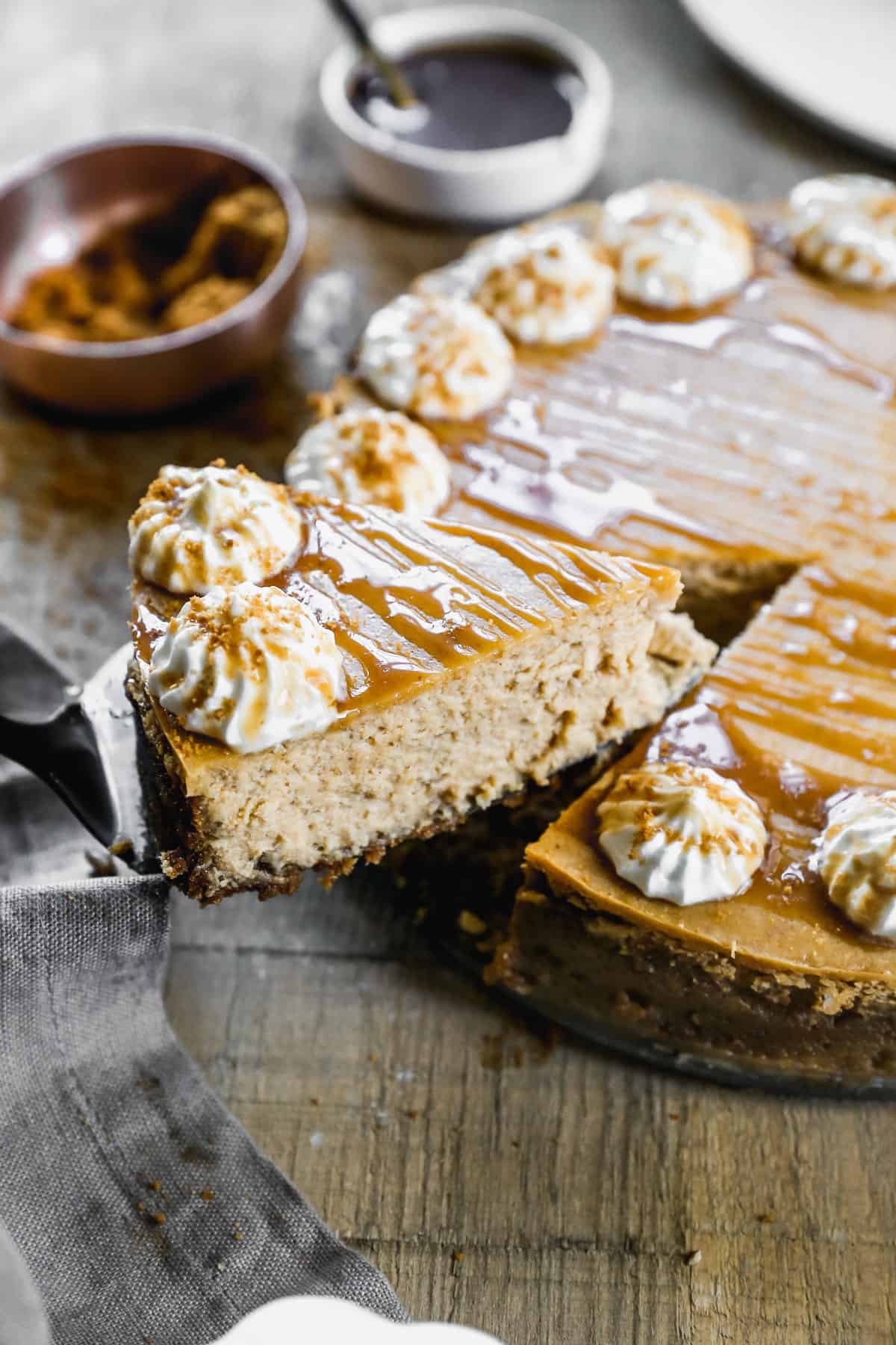 A slice of Pumpkin Cheesecake  being lifted away from the whole cake.