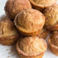 A plate with Snickerdoodle Muffins stacked on it.