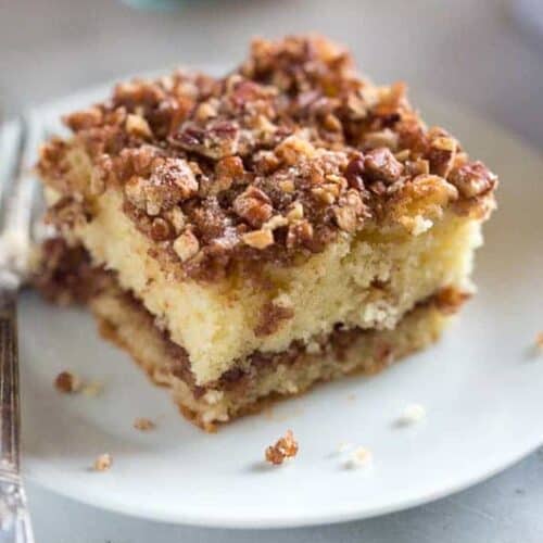 A slice of sour cream coffee cake on a plate with a fork.