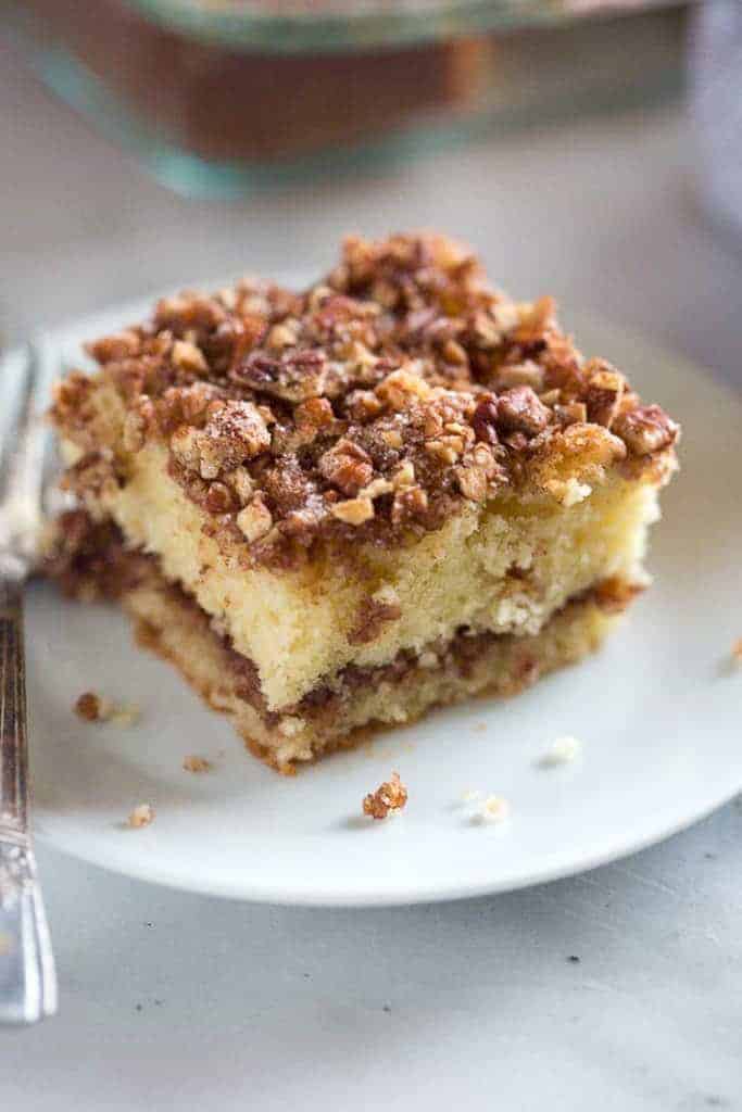 A slice of sour cream coffee cake on a plate with a fork.