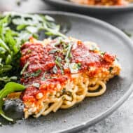 A slice of Spaghetti Pie on a plate with a green salad.