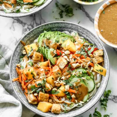 A homemade Spring Roll Bowl recipe with a sweet chili sauce, peanuts, avocado, carrot, bell pepper, cucumber, and mango.