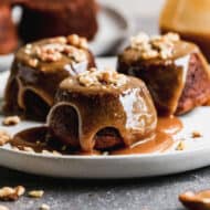 Three single serve Sticky Toffee Pudding on a plate topped with a caramel toffee sauce.