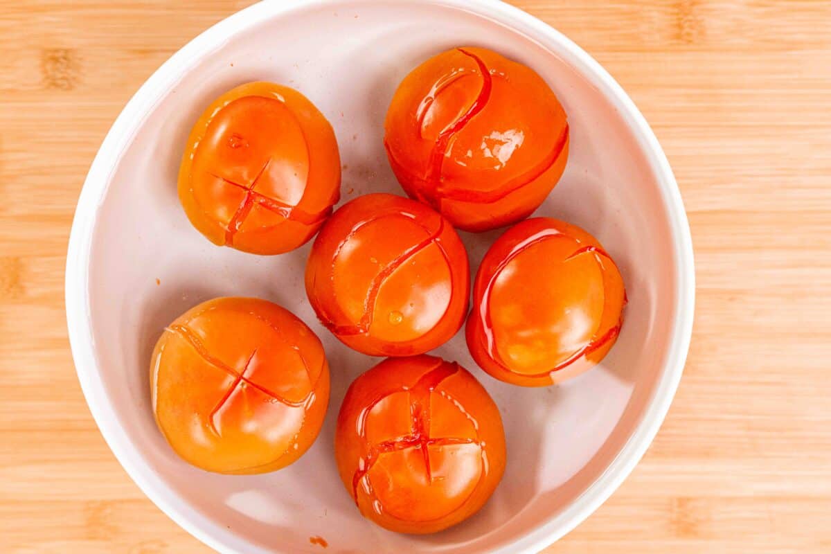 Blanched cross cut tomatoes resting in cold water.