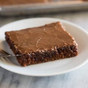 Square slice of Texas sheet cake on a small white plate with a fork.