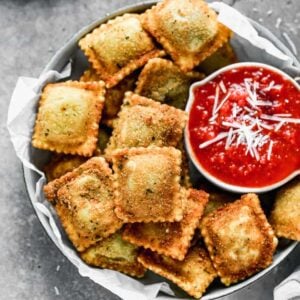 A bowl with toasted ravioli and a small bowl of marinara sauce.