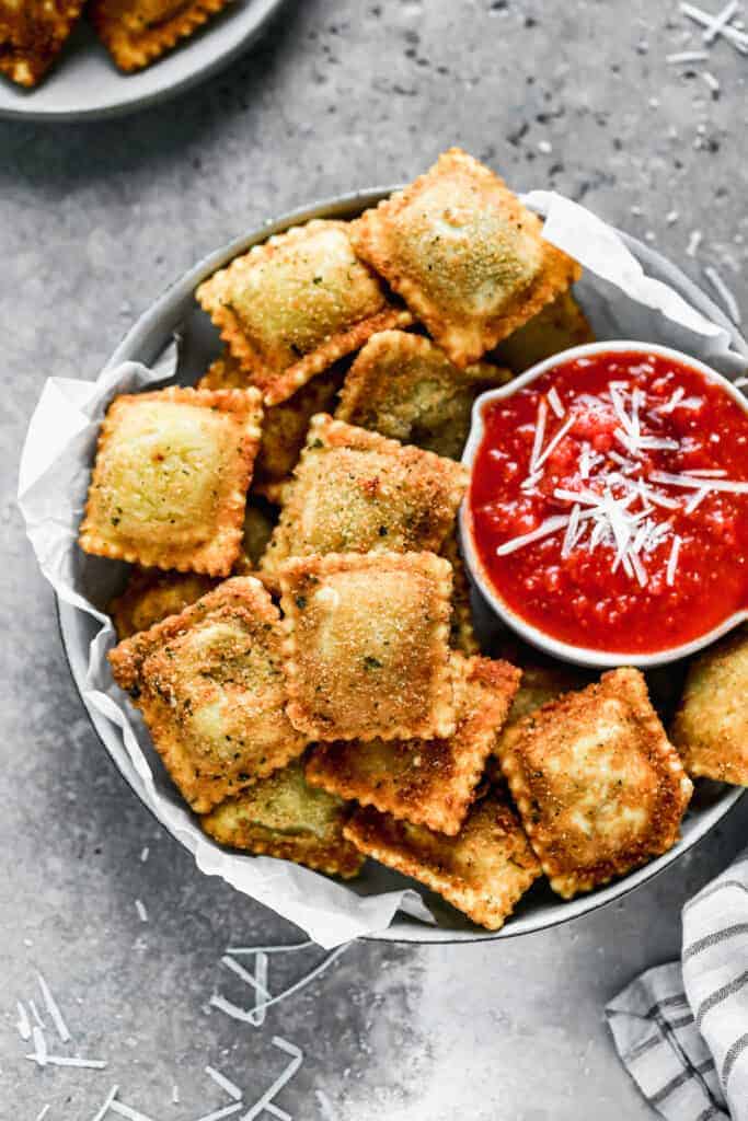 A bowl with toasted ravioli and a small bowl of marinara sauce.