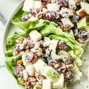 Waldorf Salad mixture served in a lettuce leaf, on a plate.