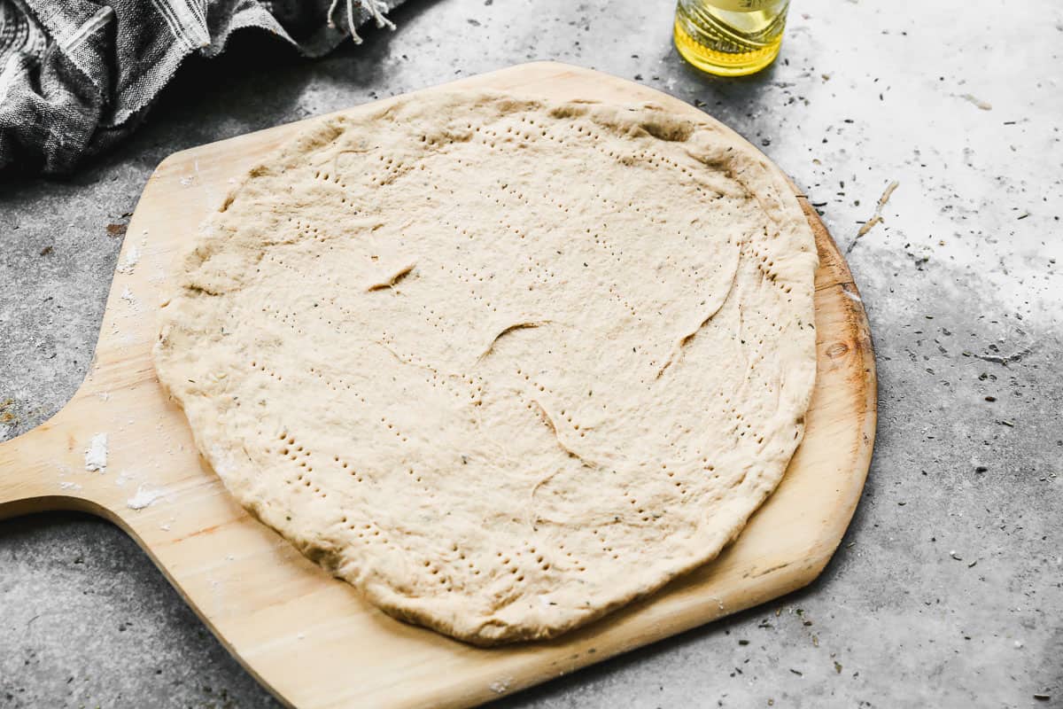 Whole wheat pizza dough rolled out and pricked with a fork.