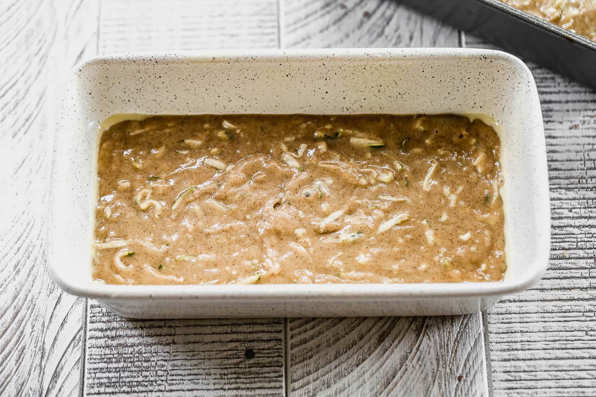 A loaf pan with zucchini bread in it, ready to bake.